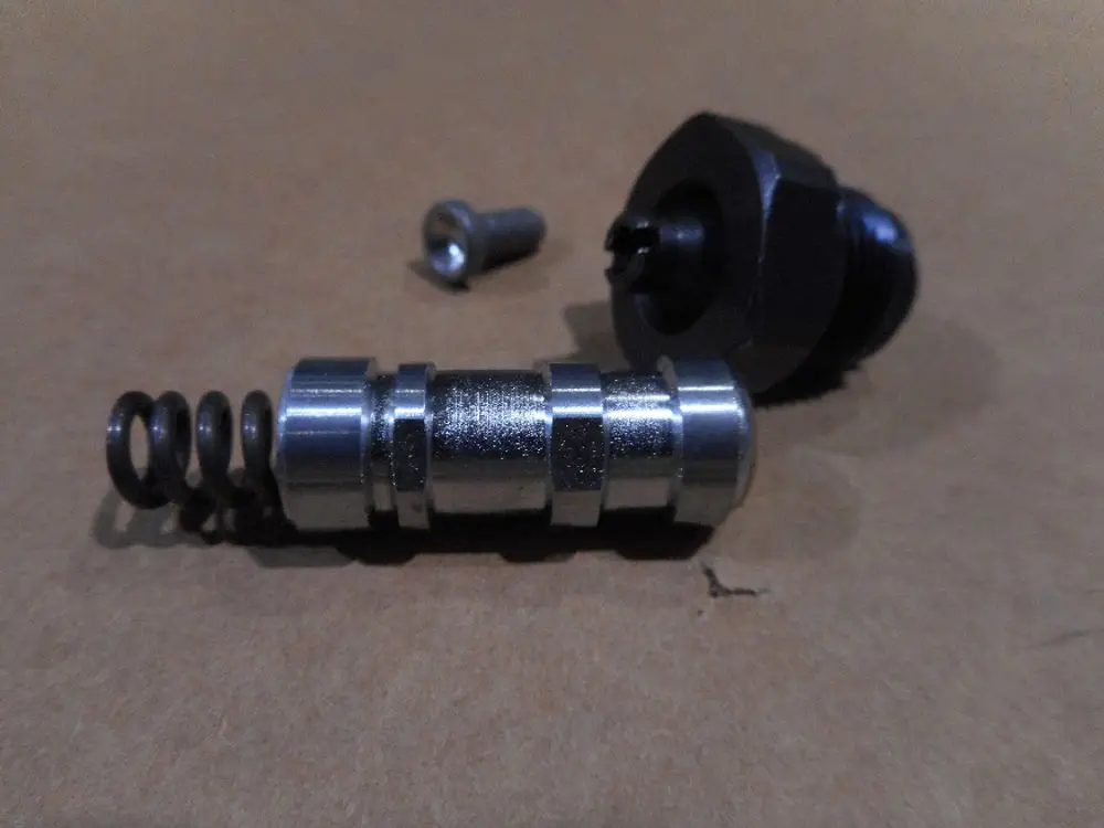 Eine Druckregelvorrichtung, bestehend aus einem Metallteil mit einer Feder und einer Schraube, von der Marke Remeha, auf einer braunen Unterlage.